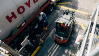Un chariot élévateur Fenwick en version ATEX se trouve à côté d’un camion-citerne transportant des produits chimiques. Un chariot élévateur Fenwick en version ATEX se trouve à côté d’un camion-citerne transportant des produits chimiques.