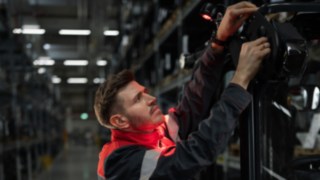 Les systèmes d’éclairage et d’avertissement Fenwick permettent une manutention sûre et précise. Un technicien de service Fenwick lors du montage d’une solution d’éclairage