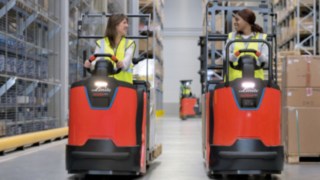 Deux collaboratrices sur des préparateurs de commandes de la série N20 de Fenwick-Linde Deux collaboratrices circulent dans un entrepôt avec des préparateurs de commandes de la série N20 de Fenwick-Linde.