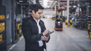 Un collaborateur de Fenwick se trouve dans l’entrepôt et prend des notes sur sa tablette.