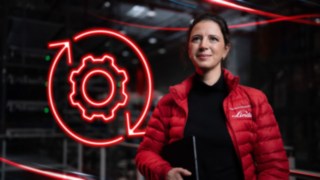Une employée de Fenwick dans un entrepôt, avec en arrière-plan le symbole LED rouge d’un engrenage.