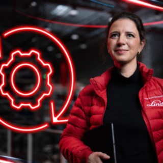 Une collaboratrice de Fenwick dans un entrepôt, avec en arrière-plan le symbole rouge d’un engrenage.