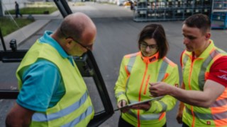 Trois personnes portant des gilets de sécurité en train de discuter : conseil sécurité chez le client. Trois personnes portant des gilets de sécurité en train de discuter : conseil sécurité chez le client.