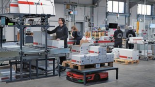 Le chariot à plateforme automatisé C-MATIC de Fenwick au milieu d’un groupe de collaborateurs d’entrepôt chez ABS Safety.