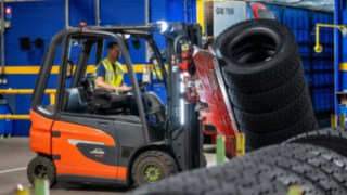 Un employé de Michelin Tyre PLC saisit une pile de pneus à l’aide d’une pince montée sur un chariot élévateur.