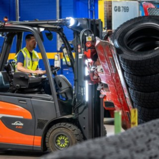 Un employé de Michelin Tyre PLC saisit une pile de pneus à l’aide d’une pince montée sur un chariot élévateur.