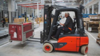Un chariot électrique Fenwick transporte une caisse grillagée