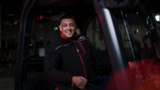 Un collaborateur Linde Material Handling est assis dans un chariot élévateur et sourit à la caméra.