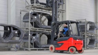 Fenwick propose des solutions pour les principaux défis intralogistiques de l’industrie automobile. Un chariot élévateur Fenwick s’approche d’un rayonnage contenant des pièces de carrosserie
