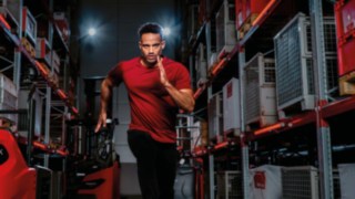 Un homme en tenue de sport court dans une allée d’entrepôt.