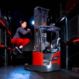 Une athlète saute haut à côté du chariot à mât rétractable Ri16 Fenwick.