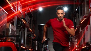 Un athlète court dans un entrepôt. En arrière-plan, on peut voir le chariot à mât rétractable Ri16 Fenwick.