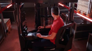 Un cariste est assis dans la cabine ergonomique du chariot à mât rétractable Ri16 Fenwick.