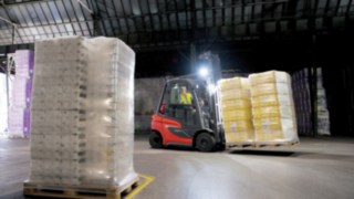 Chariot élévateur à gaz H20 - la nouvelle génération Le chariot élévateur Fenwick équipé d'éclairage transporte des marchandises dans un hall sombre